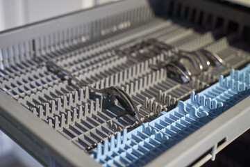 Empty dishwasher cutlery tray with three spoons lying horizontally.
