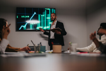 A professional delivering a presentation with a projected financial chart to team members in a meeting room, discussing trends and analysis. A collaborative atmosphere with focus on progress and