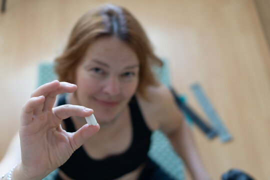 Close-up of a woman holding a white pill, symbolizing oral semaglutide treatment Rybelsus, alternative to Ozempic injections for diabetes and weight management.