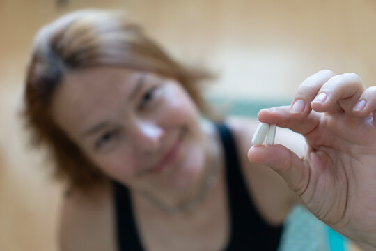 Close-up of woman holding a white pill, symbolizing oral GLP-1 therapy such as semaglutide Rybelsus or tirzepatide Mounjaro, modern diabetes and weight-loss treatment.