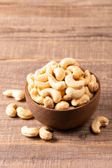 Organic roasted cashew nuts in a wooden bowl. Top view. 