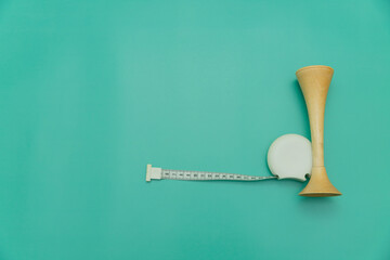 measuring tape and obstetric wooden stethoscope on green Background, Space for Text, Space for Logo