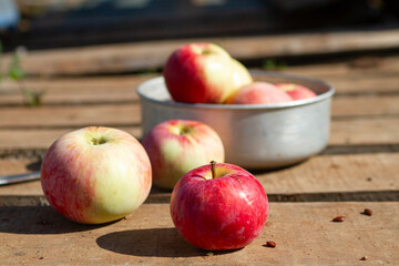 red and yellow apples on a wooden surface in the sunlight