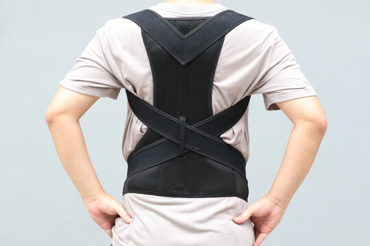 Young asian man wearing a back support belt, Lumbar brace for back trauma or Herniated Disc To relieve back pain. background