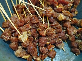 a collection of uncooked beef satay