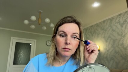 The young woman puts on a light foundation, smiling softly at her reflection in the mirror. - Powered by Adobe