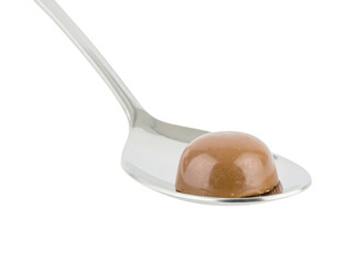 A shiny spoon holds a smooth, round chocolate truffle, highlighting its glossy surface and rich color.