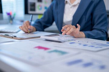 A woman is sitting at a desk with a calculator and a pen