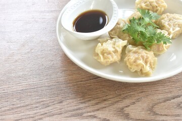steamed Chinese dumpling filling mashed pork and shrimp or dim sum topping parsley on plate dipping sour soy sauce 