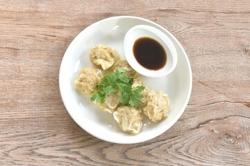 steamed Chinese dumpling filling mashed pork and shrimp or dim sum topping parsley on plate dipping sour soy sauce 