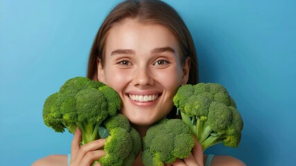 A smiling woman holding broccoli with a vibrant green color.