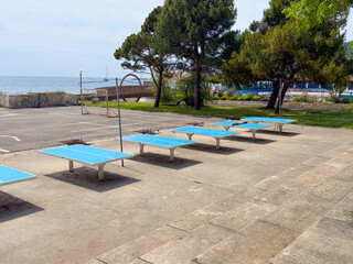 Outdoor blue table tennis area near the seaside with empty tables. Recreation, leisure and summer sport activity in open air.