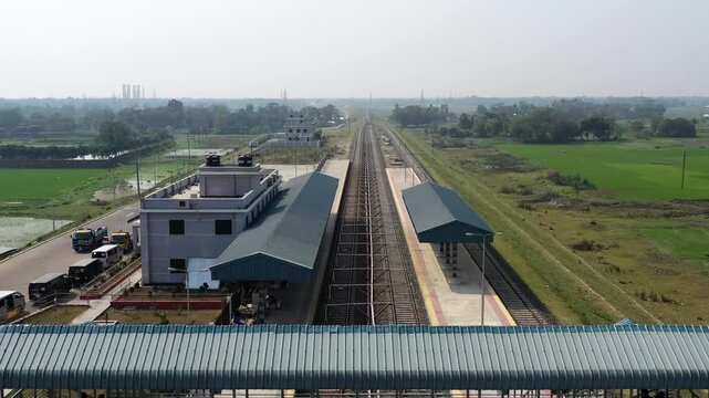 Gopalganj, Bangladesh - 20 August 2025: Aerial view of parallel railway tracks stretching into the distance, flanked by lush greenery and a modern building.