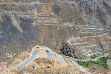 A green 4x4 motorhome driving down a very winding road with the valley below.