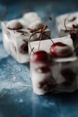 Fresh cherry in ice cubes on blue iced background. High quality photo