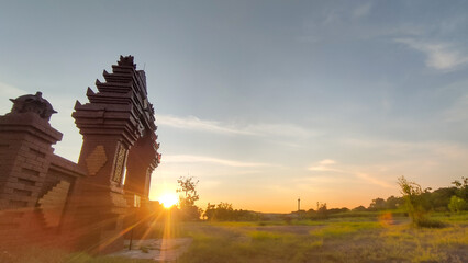 Traditional gate silhouette with sunrise background, symbolizing culture, travel, and spirituality....