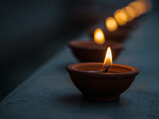 A Row of Lit Clay Diyas with a Blurry Background
