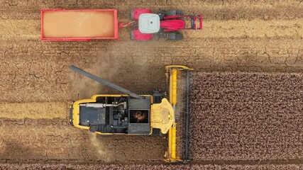 Harvester finishing unloading grain into tractor trailer and folding auger after harvest. Combine completing transfer of crop into tractor cart and retracting unloading pipe. Agricultural harvester - Powered by Adobe