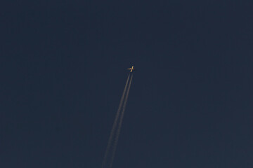 Airplane in the dark sky with a trail of white smoke.