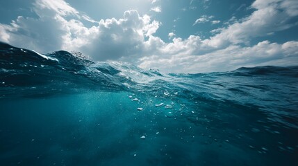 Fototapeta premium Wide view of vibrant blue ocean surface and tranquil underwater scene with sunlight breaking through clouds, creating a peaceful marine atmosphere
