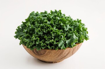Fototapeta premium Wooden bowl filled with fresh kale leaf salad on a white surface with selective focus