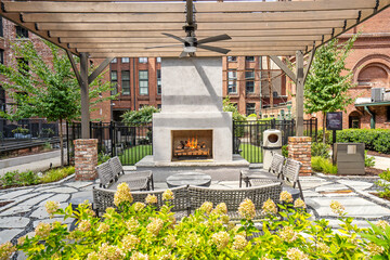 Outdoor lounge area featuring a stone fireplace surrounded by greenery and cozy seating.