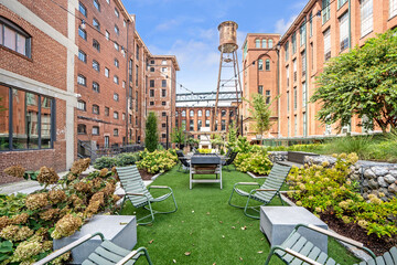 Lush courtyard garden with outdoor seating, surrounded by historic brick residential buildings