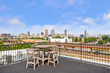 Rooftop terrace with seating overlooking a city skyline and bright blue sky.