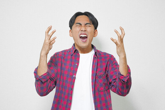 A young man expressing intense frustration, yelling with hands raised.