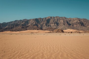 Fototapeta premium Desolate Sandy Terrain and Rocky Peaks