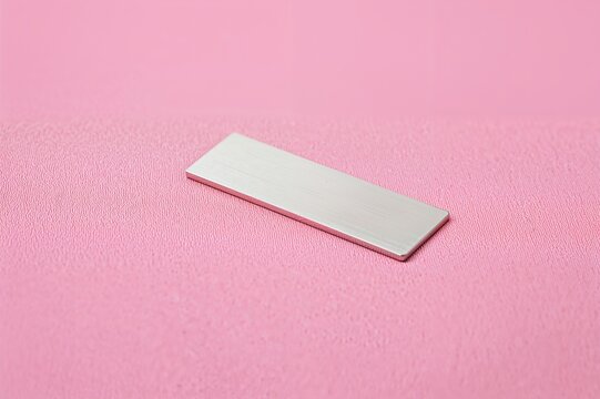 Close-up of a Shiny Metal Name Tag on a Pink Textile Surface