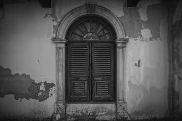 Obraz premium Monochrome photo showcasing vintage interior design featuring an arched wooden window with shutters for airflow and ample copy space.