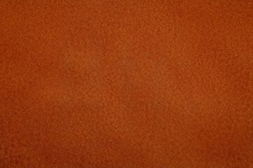 Fototapeta premium Close-up view of dark orange suede material background with soft matte velvet texture and vignette effect.