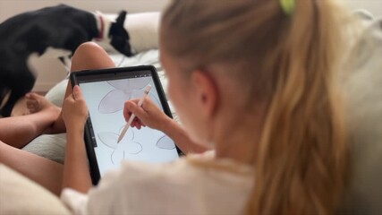 Woman drawing on the tablet and cuddling her dog