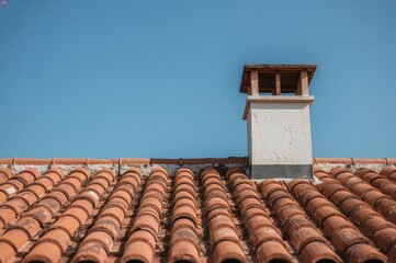 Architecture featuring rooftop chimney, ventilation, and tiled surfaces under clear blue skies with an emphasis on heritage and eco-friendly terracotta materials