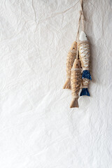 Festive wooden hanging fish decorations on paper texture background.