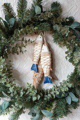 green Christmas wreath with wooden fish decoration on paper texture background.