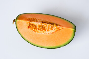 Top view of a single wedge of ripe cantaloupe, showing the vibrant orange flesh and the small cluster of seeds, isolated on a white background.