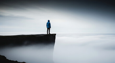 Obraz premium Solitary figure standing on the edge of a cliff overlooking a vast expanse of clouds and mist