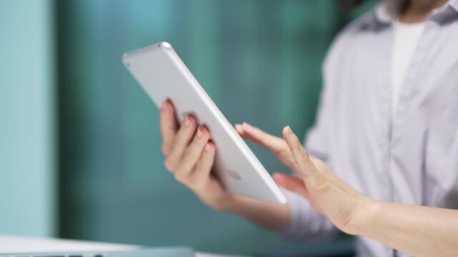 Close up of female hands holding using digital tablet at workplace in business office. Asian businesswoman working on computer application, typing message, chatting online, browsing, checking email