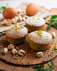 Pistachio muffins on a wooden surface.