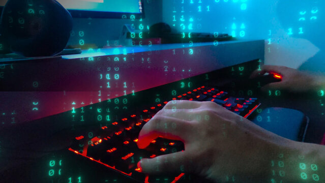 Hacker or programmer hands typing on a backlit keyboard with binary code overlay. Cybersecurity, data, and technology concept. Close-up of a person coding or gaming in a dark room with neon lights.