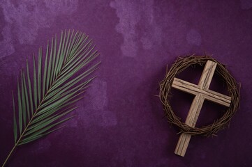 Religious Symbols of Easter: Crown of Thorns, Wooden Cross, and Palm Leaf on Purple Backdrop