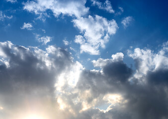 Clouds in blue sky with sunlight. Bright atmosphere with beams and rays, fluffy formations and