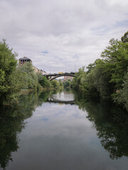 Obraz premium Garca Ojeda Bridge, which provides access to the Templar Castle of Ponferrada, located over the river Sil and reflected in it with many trees and vegetation on both banks of the river