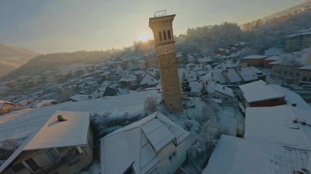 FPV drone flight over a snowy historic town at sunrie.