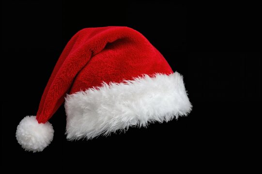 Festive Santa Claus hat on dark backdrop with transparent cutout