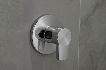 Detailed shot of shiny metallic toilet flush controls fixed on a neutral-toned tiled surface, showcasing stylish bathroom aesthetics and practical features in current home decor