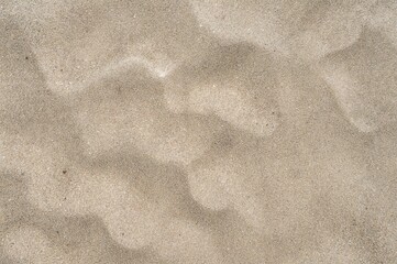 Overhead close-up view of a heap of light beige sand showing detailed granular texture