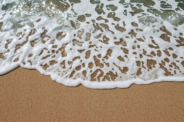 Coastal scene featuring large surf and rippled tan sand, serene vibe, summer vacation setting, artistic seaside background